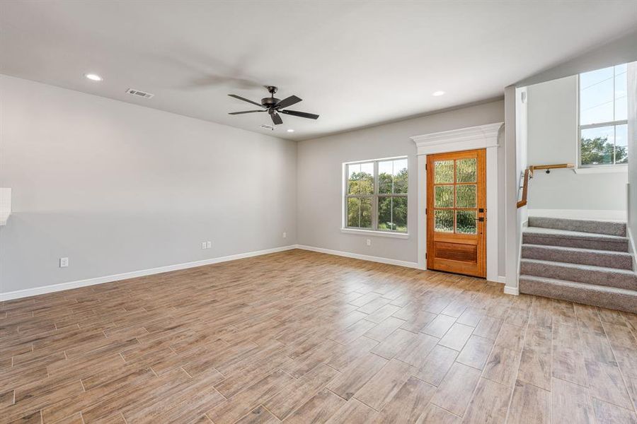 Unfurnished living room featuring light wood-type flooring and ceiling fan