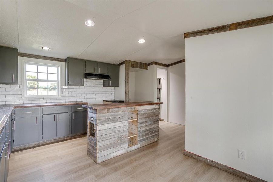 Kitchen featuring decorative backsplash, light hardwood / wood-style floors, and crown molding