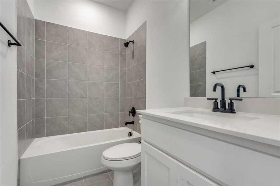 Full bathroom with tiled shower / bath, vanity, tile patterned flooring, and toilet