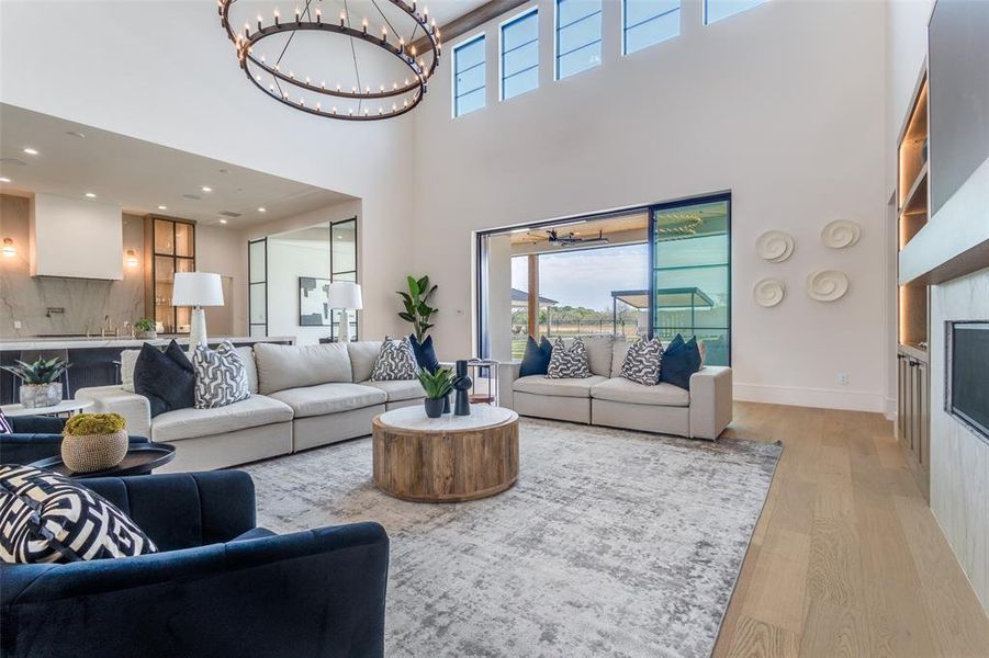 Living room featuring a chandelier, light wood-type flooring, and a high ceiling