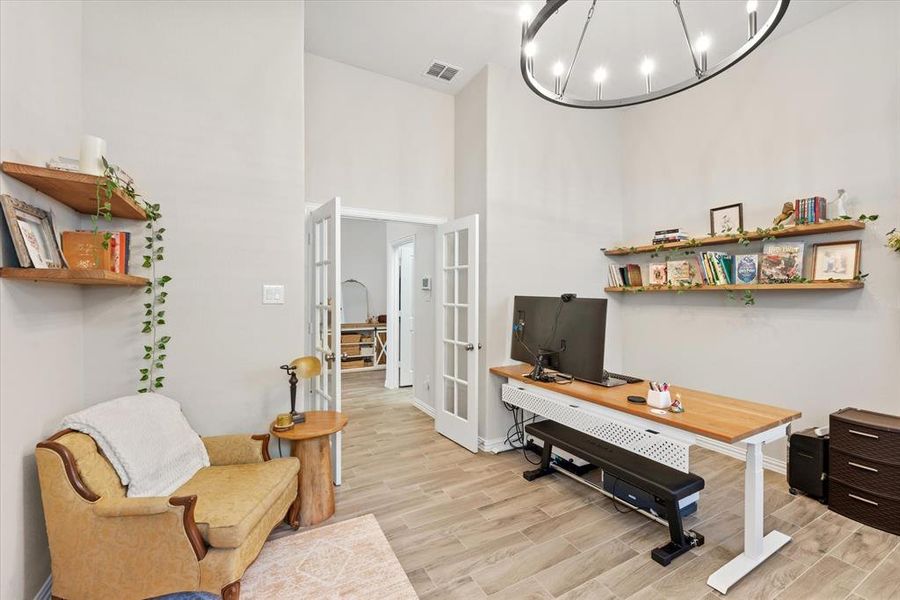 Office featuring a gorgeous chandelier, a towering ceiling, and french doors