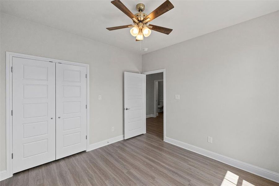 Unfurnished bedroom with wood-type flooring, a closet, and ceiling fan