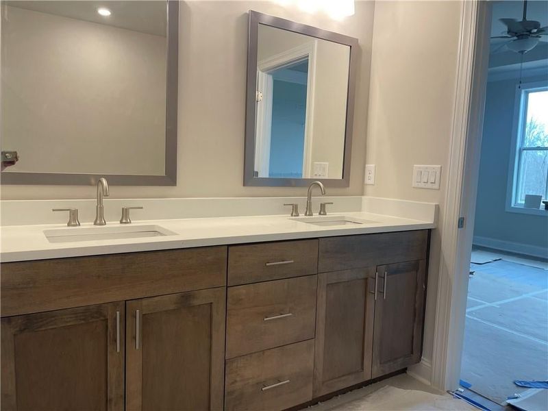 This stylish space features double vanity with quartz countertops  and plenty of storage.