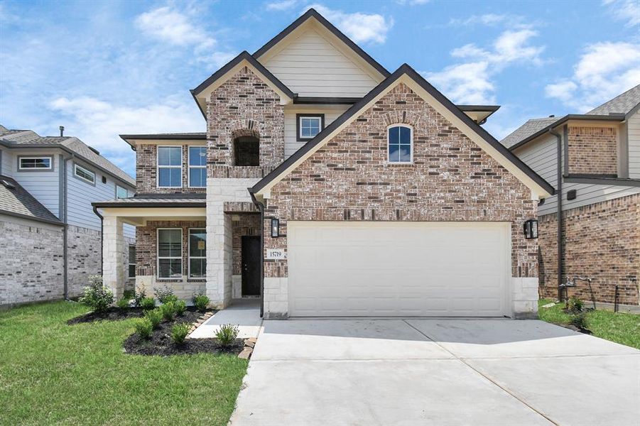 This home boasts lush green grass and meticulous landscaping. Its premium elevation showcases an exquisite blend of brick and stone features, complemented by modern coach lighting