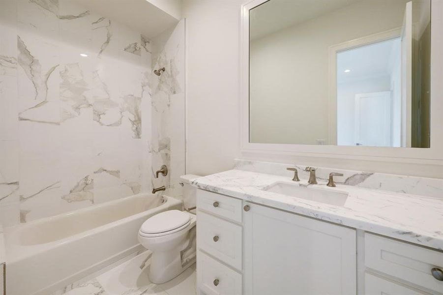 This ensuite bath is light and bright with marble floor, counter top and tub/shower surround and a beautifully framed mirror.