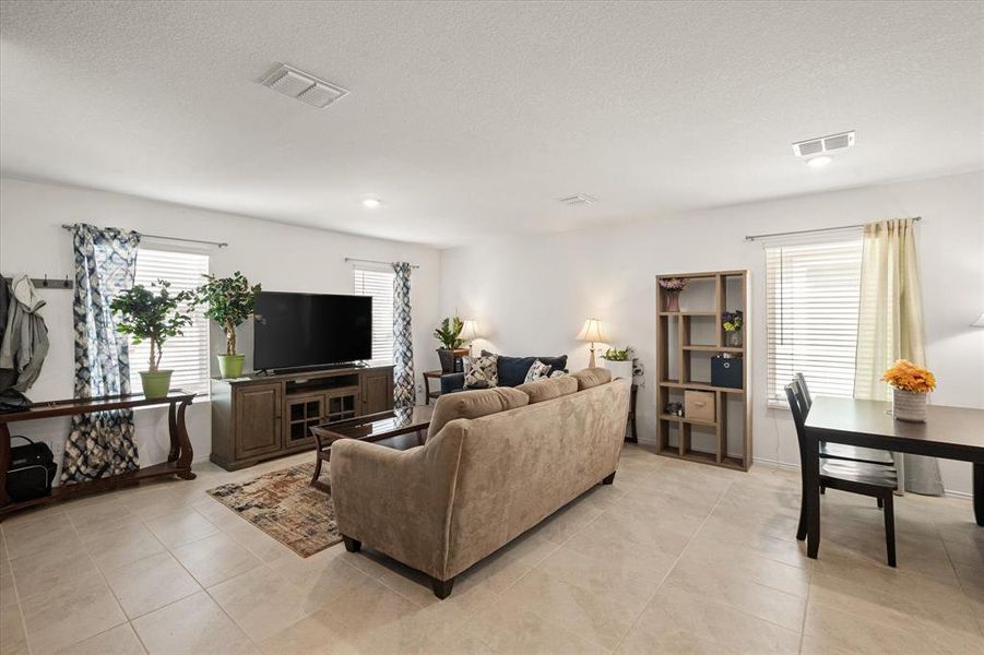 Tiled living room with a textured ceiling and plenty of natural light