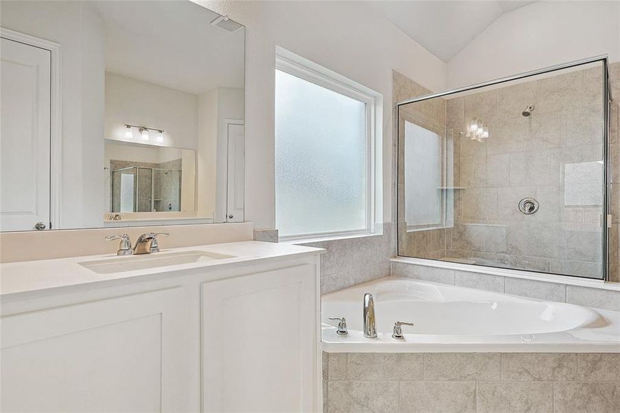 Bathroom with shower with separate bathtub, vaulted ceiling, and vanity