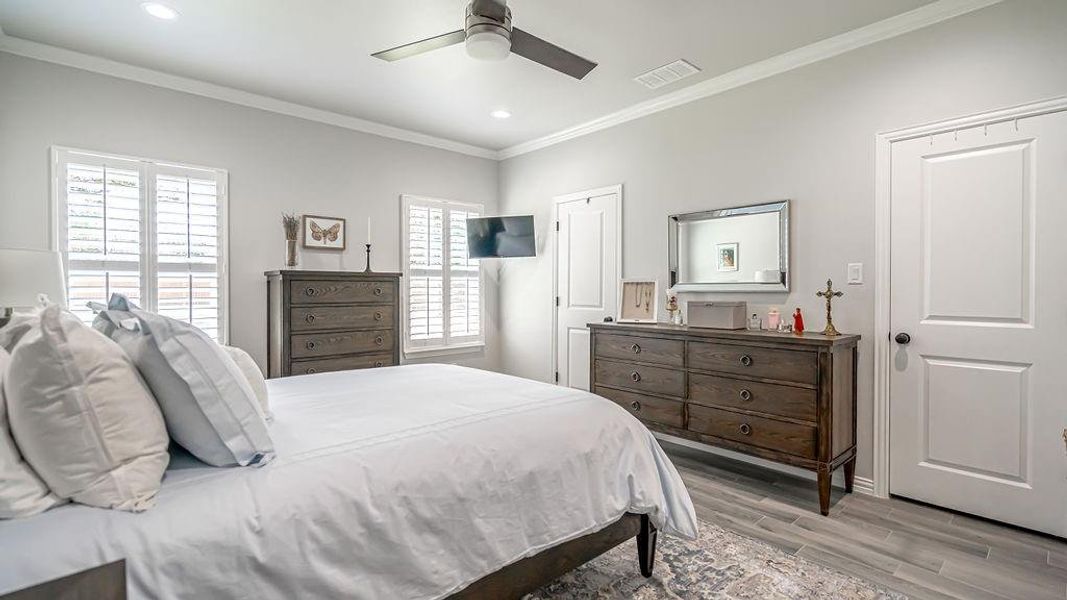 Bedroom featuring ceiling fan, crown molding, light hardwood / wood-style floors, and multiple windows