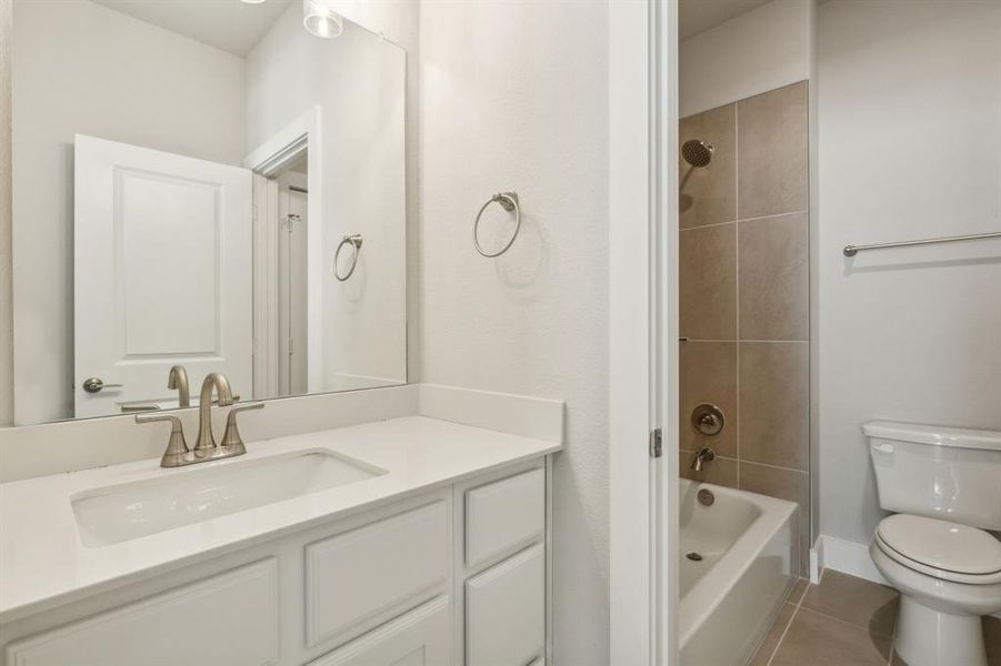 Full bathroom with toilet, vanity, tiled shower / bath, and tile patterned flooring