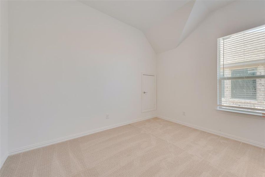 Carpeted empty room featuring vaulted ceiling