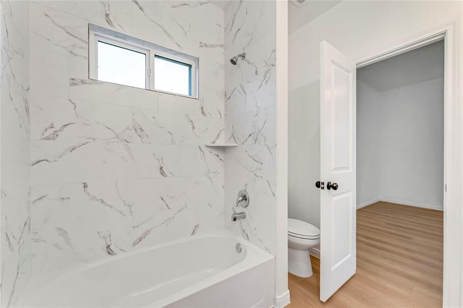 The master bathroom's tub/shower combo and sleek toilet create a spa-like retreat, offering a sanctuary for relaxation and rejuvenatio