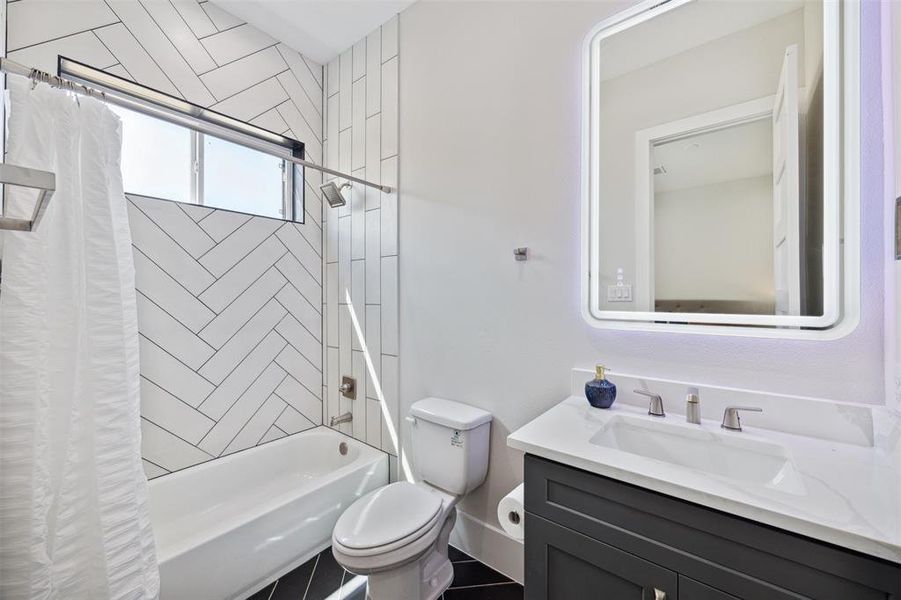 En-suite bath off of secondary bedroom has a lighted mirror, quartz topped vanity and tub/shower combo.