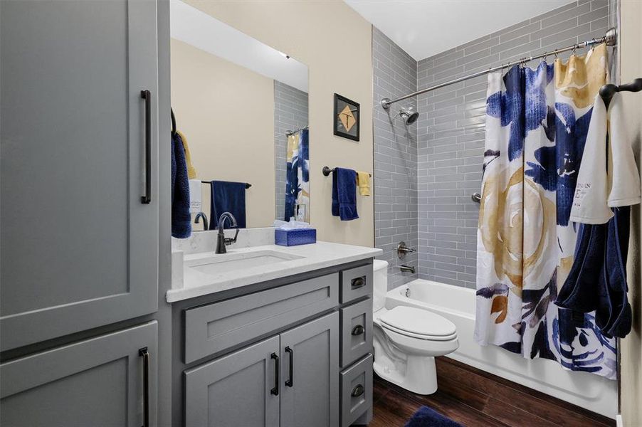 Full bathroom with vanity, toilet, shower / tub combo, and hardwood / wood-style floors