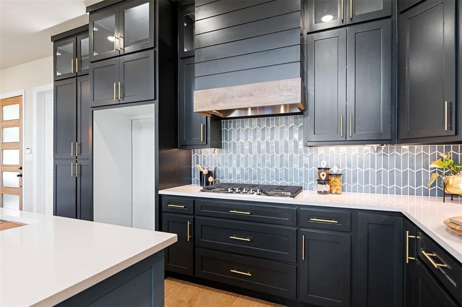 Kitchen featuring tasteful backsplash, light wood-type flooring, stainless steel gas cooktop, and custom range hood