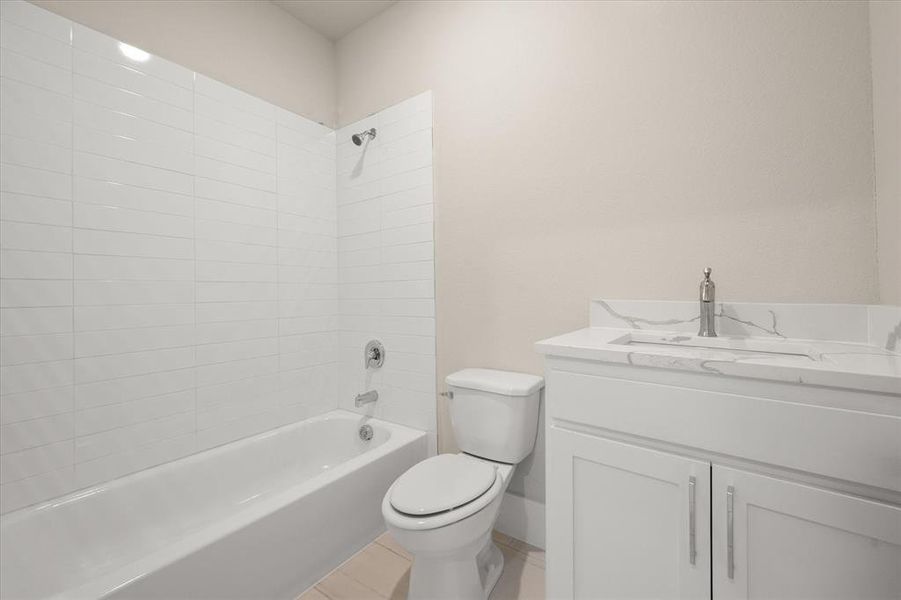 Full bathroom featuring tile patterned floors, vanity, tiled shower / bath combo, and toilet