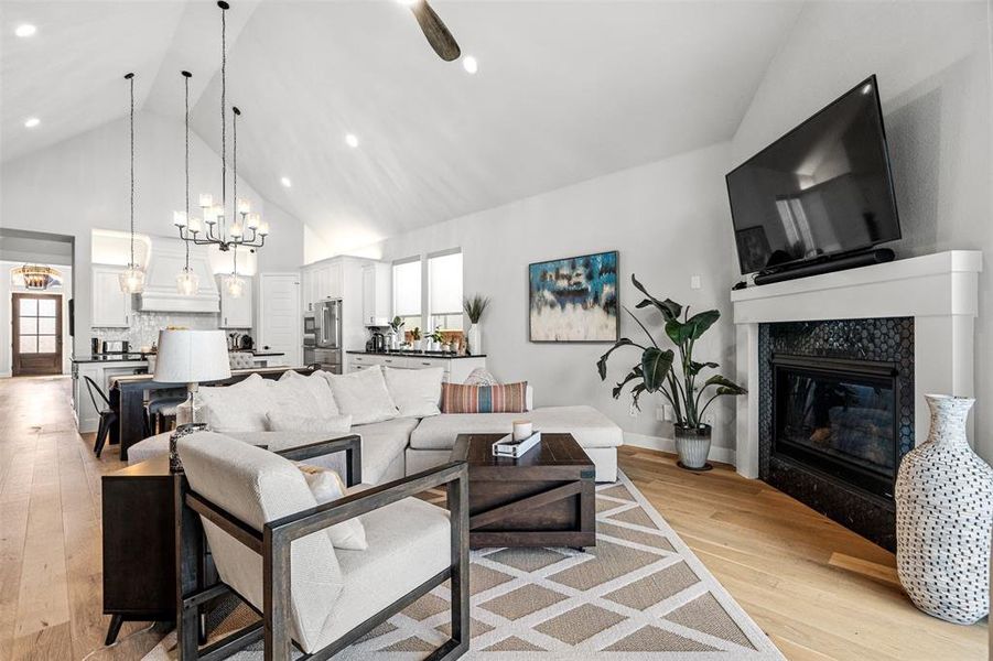 Living room with high vaulted ceiling, a wealth of natural light, a fireplace, and light wood-type flooring