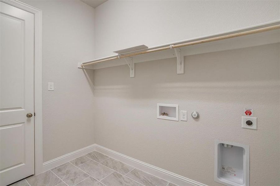 Clothes washing area featuring electric dryer hookup, light tile patterned flooring, washer hookup, and hookup for a gas dryer