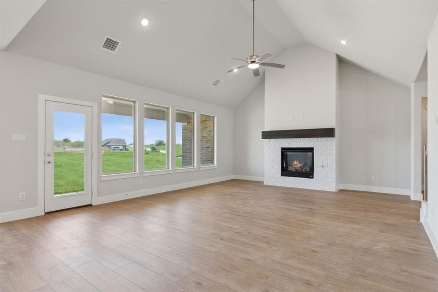 Unfurnished living room with light hardwood / wood-style floors, high vaulted ceiling, and ceiling fan