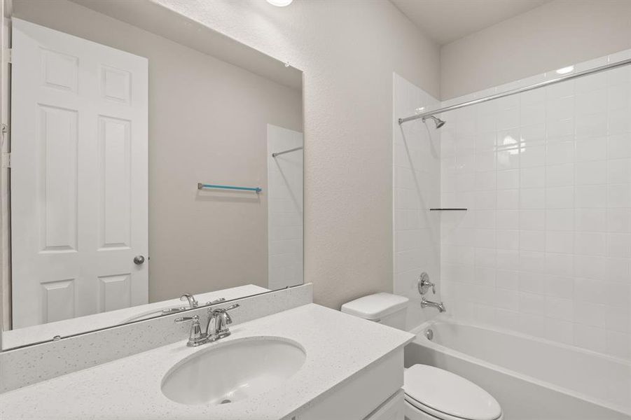 The secondary bath features tile flooring, white cabinetry and light countertops and a shower/tub combo. Perfect for accommodating any visiting family and friends.