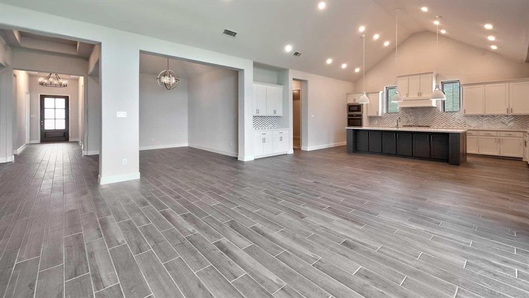 Kitchen featuring white cabinets, hardwood / wood-style flooring, decorative light fixtures, and an island with sink