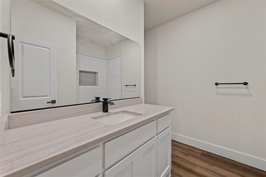 Bathroom featuring hardwood / wood-style flooring, vanity, and tiled shower