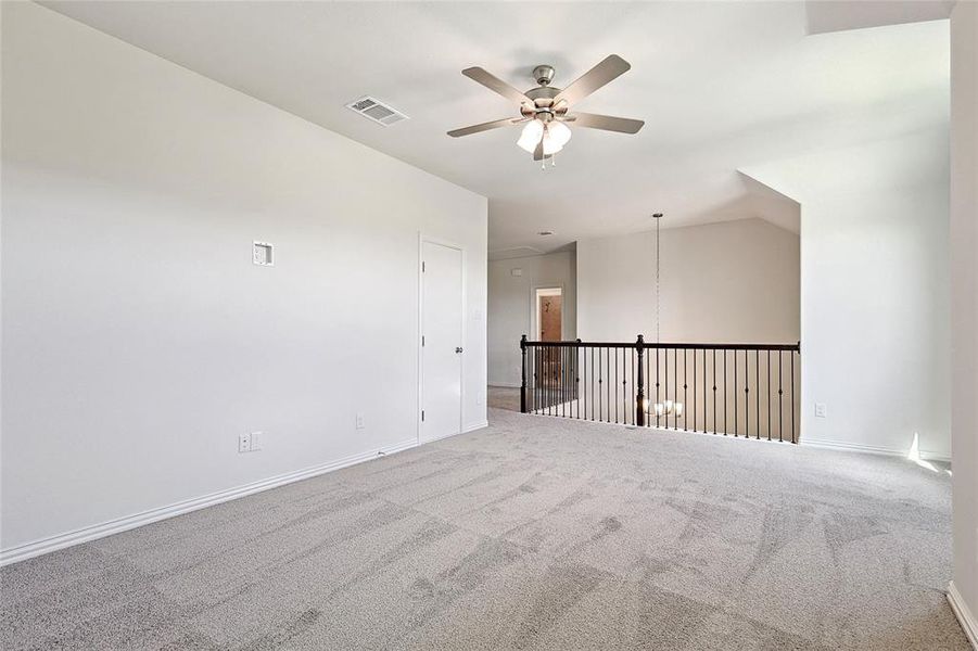 Carpeted empty room featuring vaulted ceiling and ceiling fan