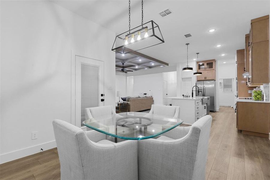 Dining area with light hardwood / wood-style floors, ceiling fan, and coffered ceiling