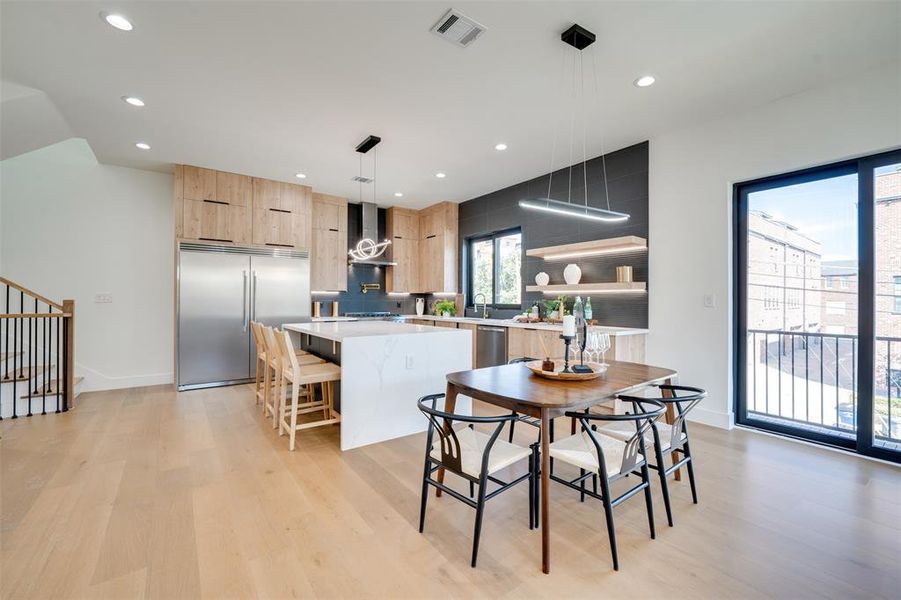 Kitchen with a breakfast bar area, appliances with stainless steel finishes, a kitchen island, light hardwood / wood-style floors, and decorative light fixtures