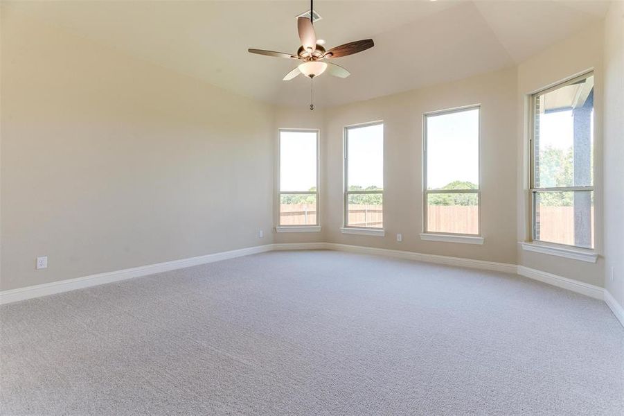 Empty room featuring ceiling fan, vaulted ceiling, and light colored carpet