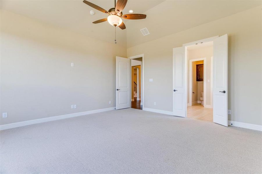 Unfurnished bedroom featuring high vaulted ceiling, ceiling fan, and light carpet