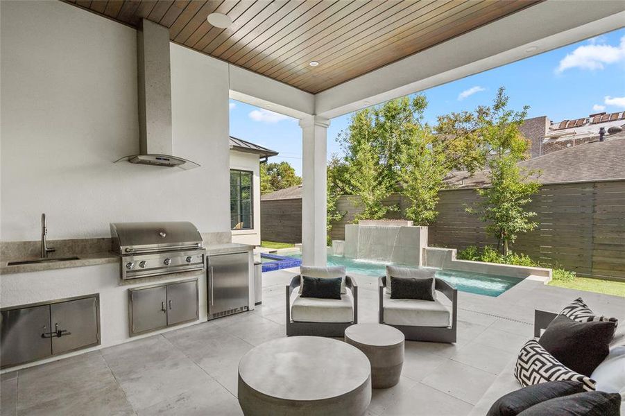 Outside, the summer kitchen is perfect for entertaining, featuring a built-in Artisan stainless steel grill with a vent hood, a convenient sink, EdgeStar mini fridge, and ample counter space for food preparation. Custom cabinetry provides additional storage for grilling essentials, while a built-in beverage fridge ensures drinks are always chilled.