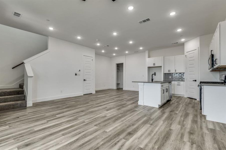 Kitchen with light hardwood / wood-style flooring, sink, a center island with sink, and white cabinets