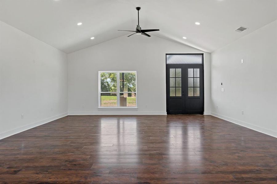 Unfurnished living room featuring hardwood / wood-style flooring, french doors, high vaulted ceiling, and ceiling fan
