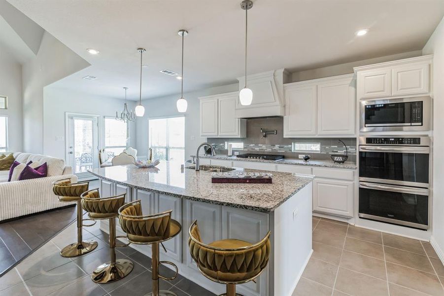 Kitchen with white cabinetry, decorative backsplash, light stone countertops, and stainless steel appliances