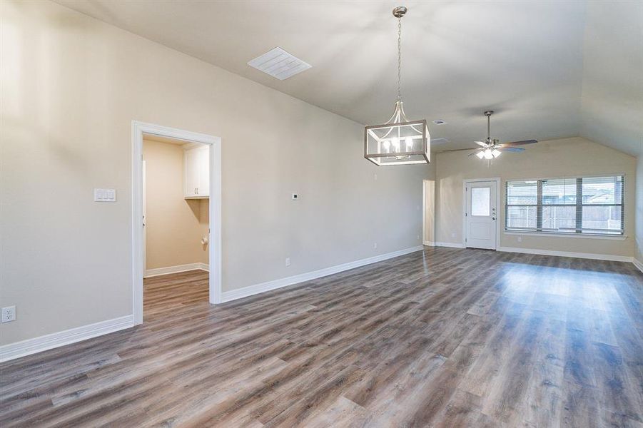 Living room with hardwood / wood-style floors, vaulted ceiling, and ceiling fan with notable chandelier