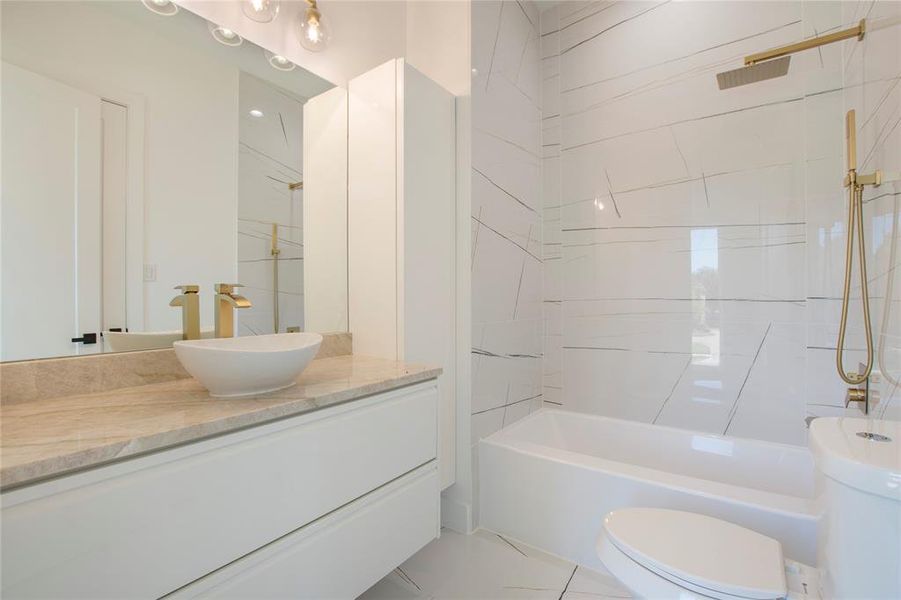 Full bathroom featuring vanity, tiled shower / bath combo, and toilet