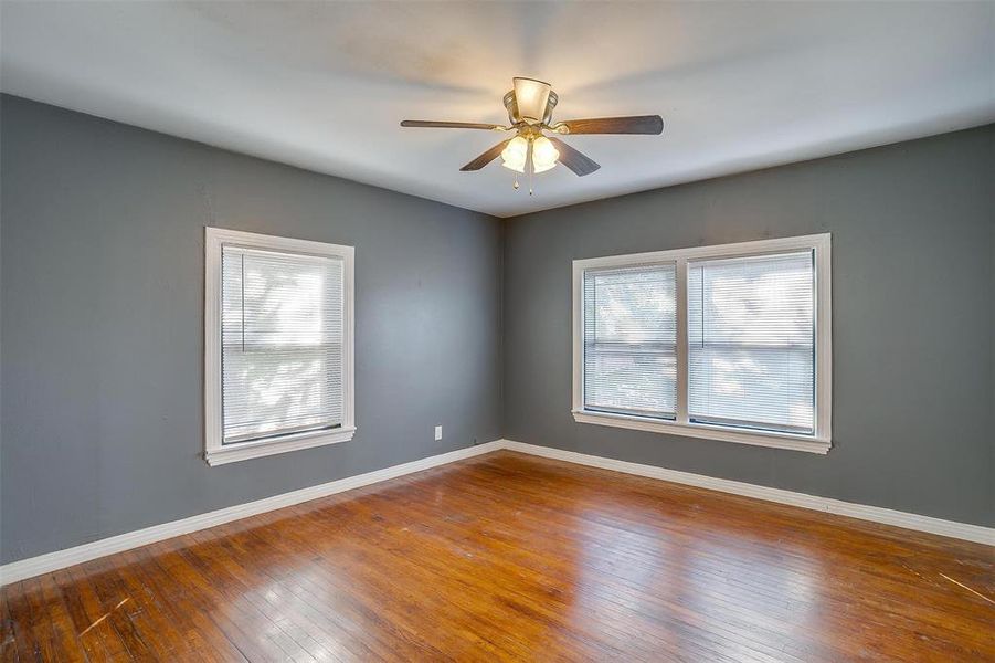 Empty room with wood-type flooring, plenty of natural light, and ceiling fan