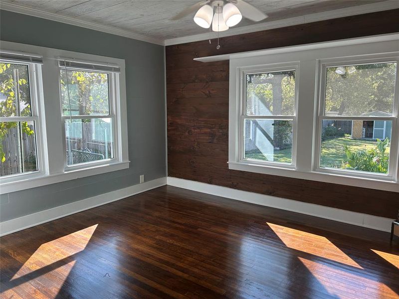 Bedroom, featuring crown molding, ceiling fan, wooden walls, and dark hardwood / wood-style flooring