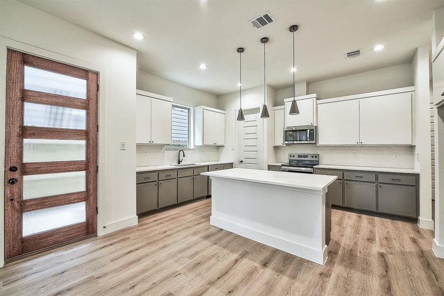 Kitchen featuring a kitchen island, stainless steel appliances, gray cabinetry, and white cabinetry