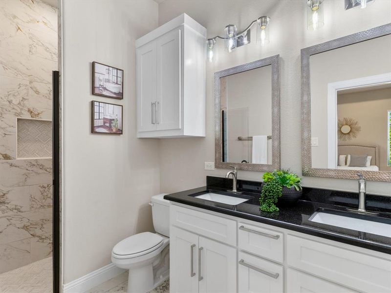 Bathroom with a tile shower, vanity, and toilet