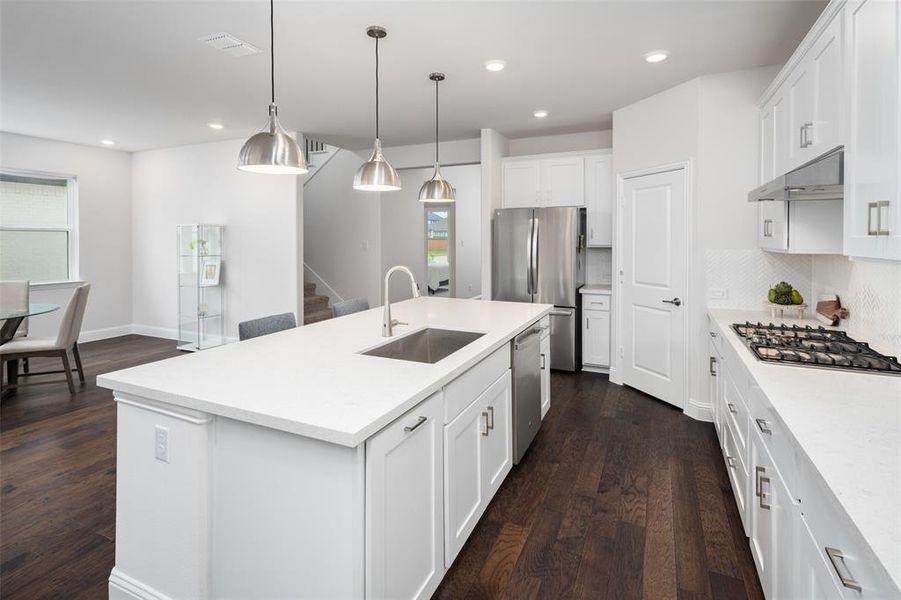 Kitchen featuring dark hardwood / wood-style flooring, a kitchen island with sink, stainless steel appliances, sink, and white cabinets