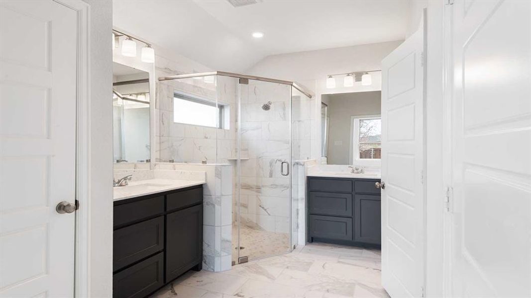 Bathroom featuring vanity, lofted ceiling, a shower with shower door, and a wealth of natural light