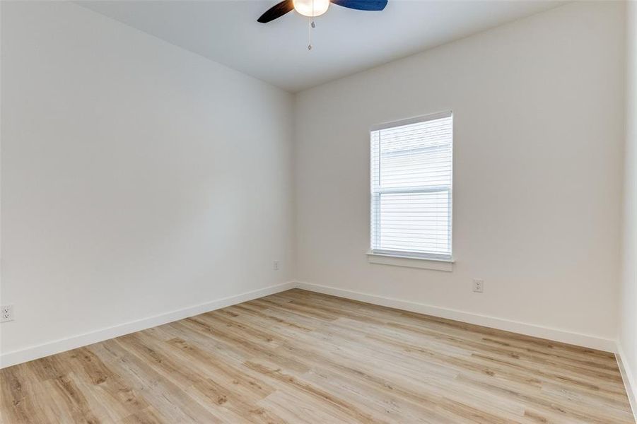 Empty room with ceiling fan and light hardwood / wood-style flooring