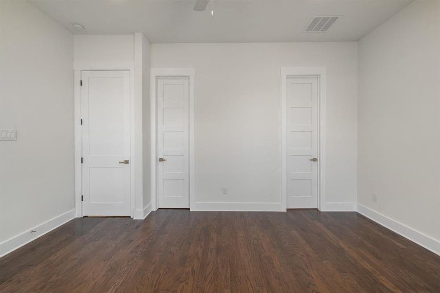 Unfurnished bedroom featuring dark wood-type flooring and ceiling fan