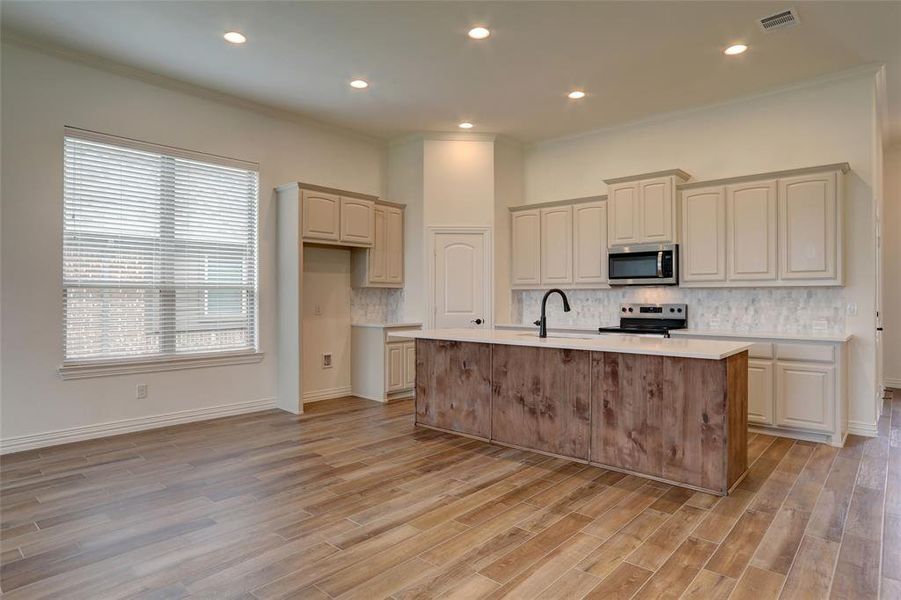 Kitchen featuring light hardwood / wood-style floors, tasteful backsplash, an island with sink, stainless steel appliances, and sink