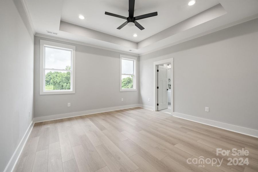 Primary bedroom with tray ceilings and 52" ceiling fans