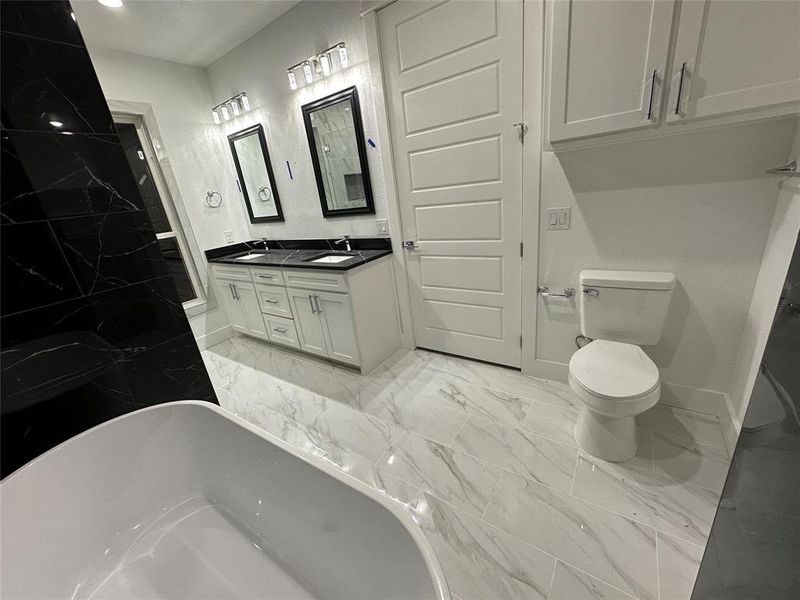 Bathroom featuring porcelain tile flooring, double sink vanity, toilet, and a bathtub with Toilet Cabinet