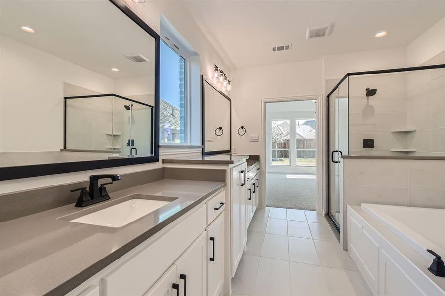 Bathroom featuring vanity, shower with separate bathtub, and tile patterned floors