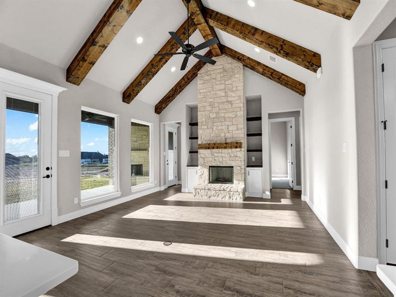 Unfurnished living room with beam ceiling, dark wood-type flooring, ceiling fan, a fireplace, and high vaulted ceiling