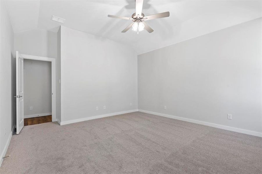 Unfurnished bedroom featuring carpet floors, ceiling fan, and vaulted ceiling